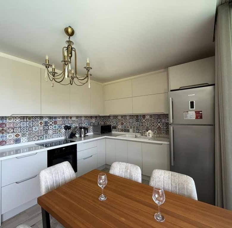 Bright, contemporary kitchen with white cabinets and colorful tiled backsplash in Yalıkavak Bodrum.