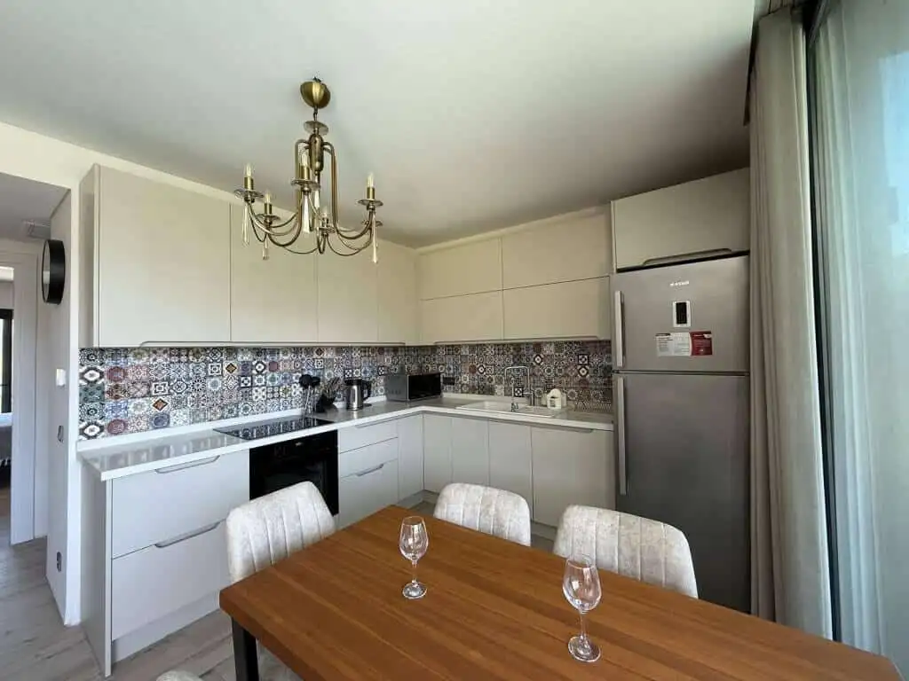 Bright, contemporary kitchen with white cabinets and colorful tiled backsplash in Yalıkavak Bodrum.