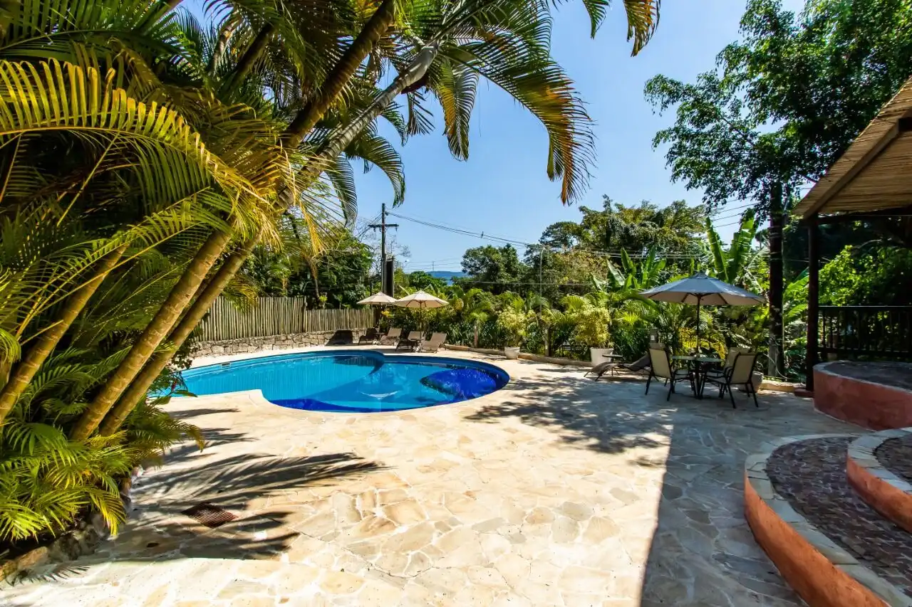 Beautiful outdoor pool area at a boutique hotel in Ilhabela, surrounded by lush tropical greenery.