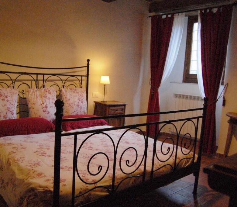 Elegant bedroom with wrought iron bed and floral bedding in a cozy home.