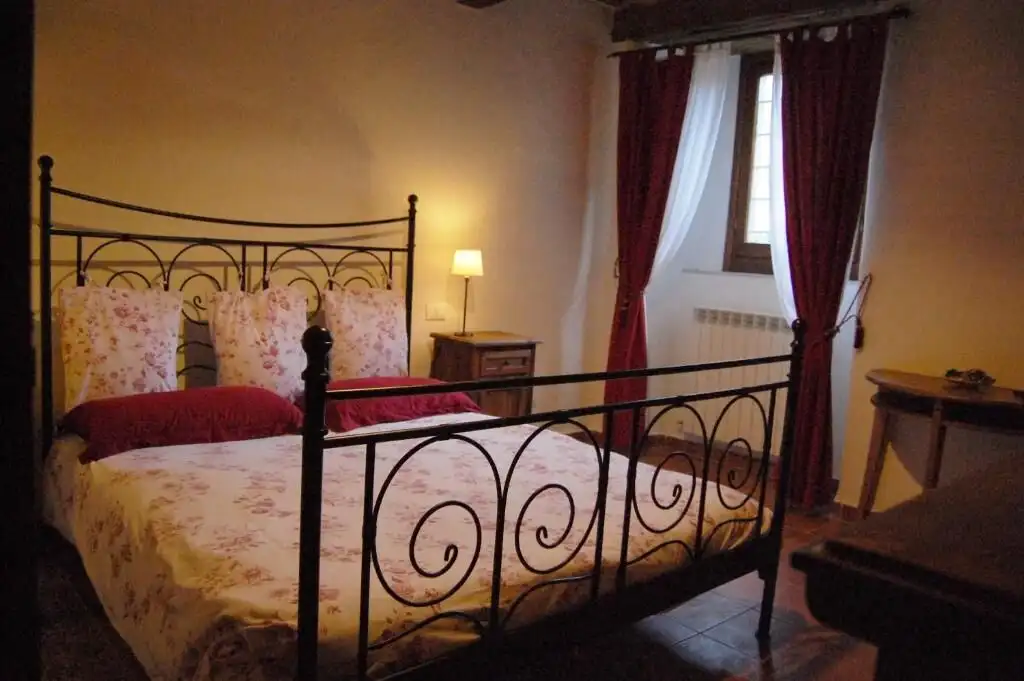 Elegant bedroom with wrought iron bed and floral bedding in a cozy home.