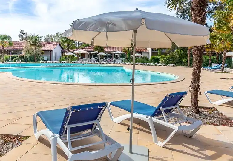 Luxurious outdoor pool with sun loungers and umbrella, perfect for relaxing and enjoying sunny weath.