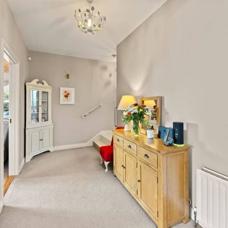 Bright hallway with a wooden sideboard and floral decor.