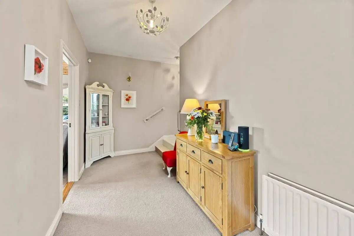 Bright hallway with a wooden sideboard and floral decor.