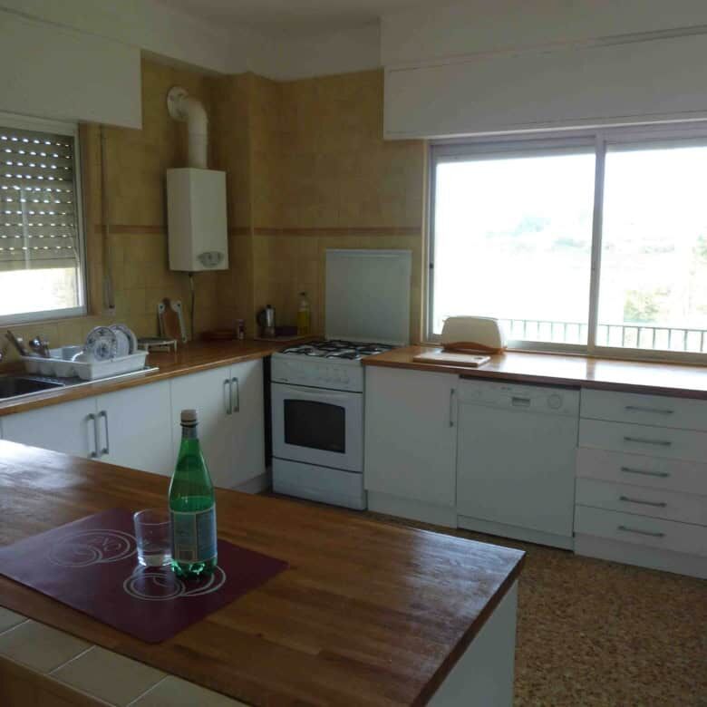 Spacious kitchen with large windows, white cabinets, and wooden countertops in a beautiful Valencia.