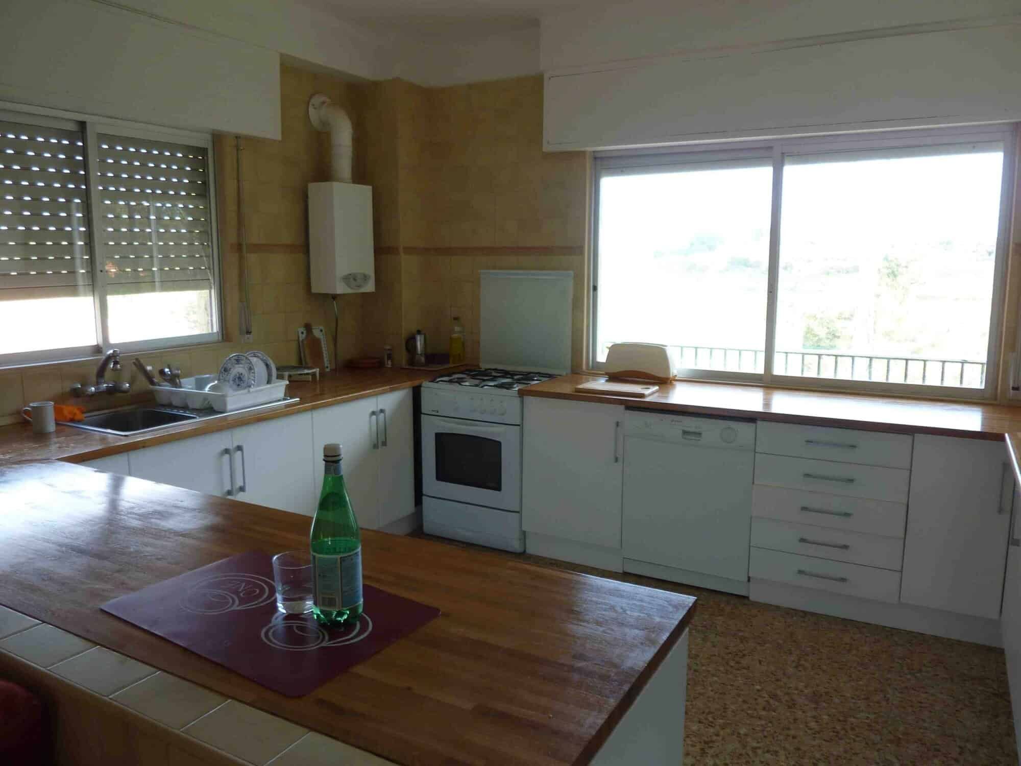 Modern kitchen in Valencia villa for sale Spacious kitchen with large windows, white cabinets, and wooden countertops in a beautiful Valencia.