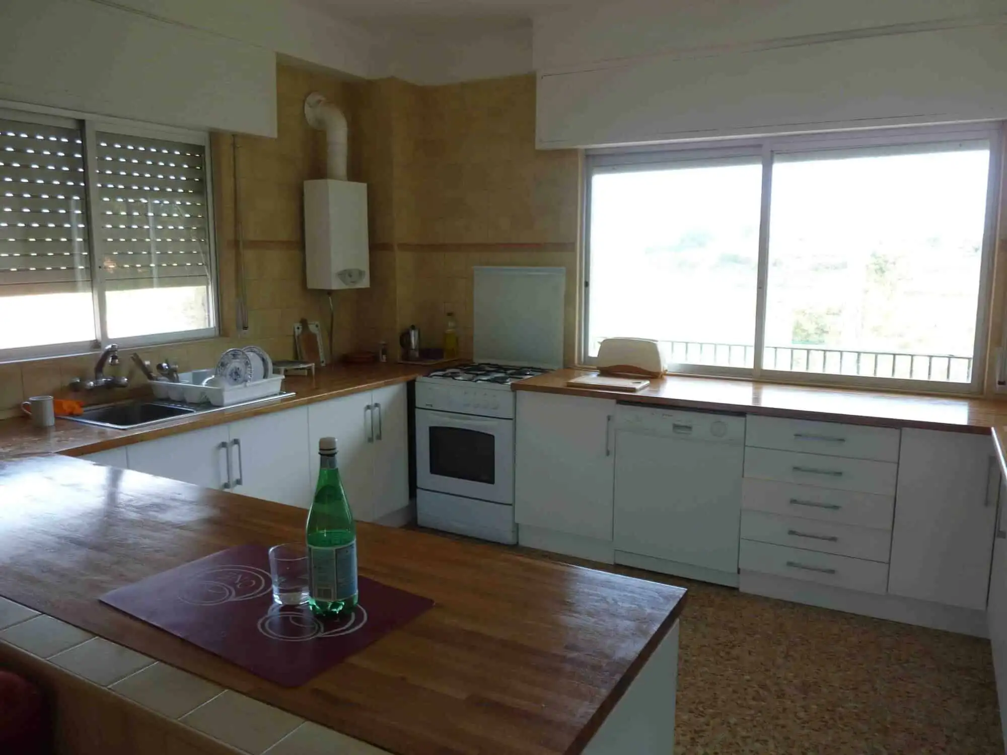 Spacious kitchen with large windows, white cabinets, and wooden countertops in a beautiful Valencia.