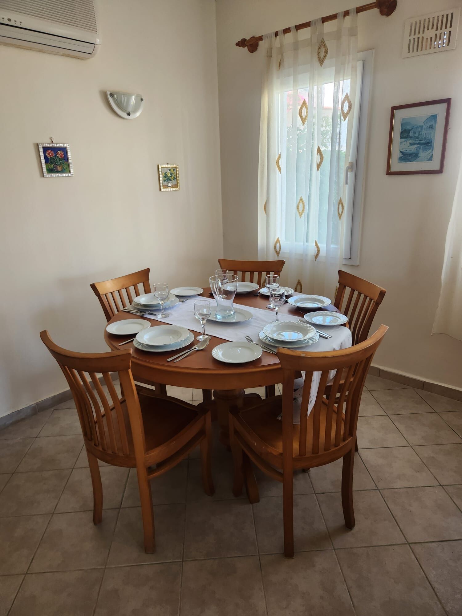 Luxury 3 Bed Villa For Sale in Grand Sea View 1 Gumusluk Elegant dining room with wooden table and six chairs, bright natural light, and seaside artwork.
