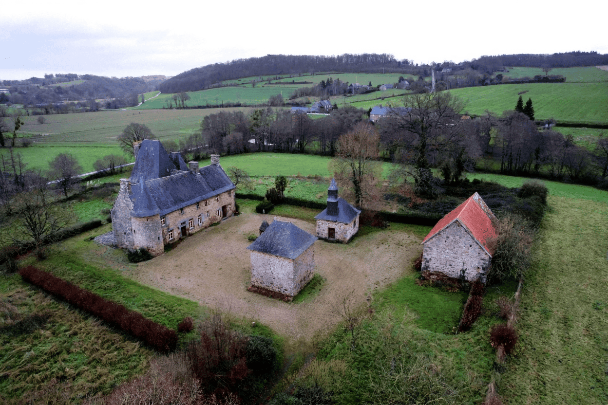 Luxury 5 Bed Le Manoir de Dougeru Le Manoir de Dougeru estate in Normandy with historic buildings and lush landscape.