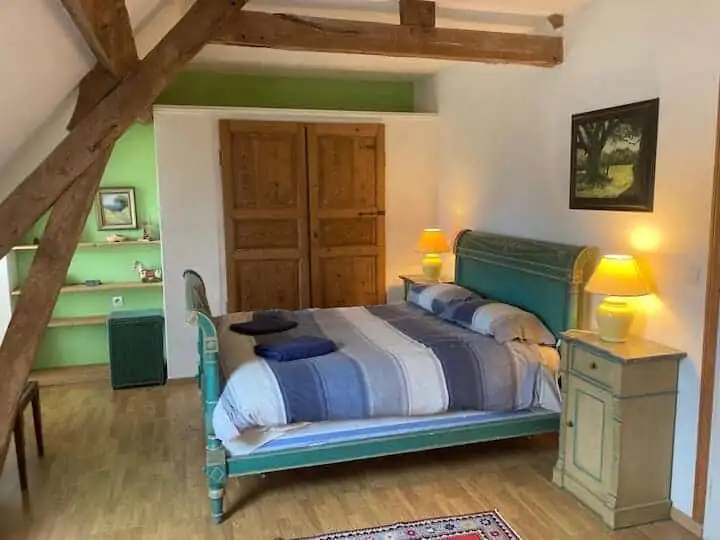 Spacious bedroom with a large bed, wooden beams, and charming decor in a property for sale in Sorrus.