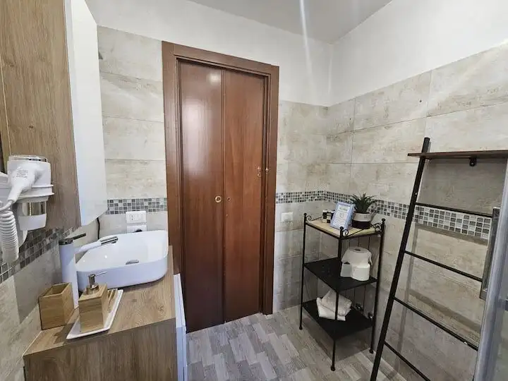 Bright bathroom featuring a wooden door, tiled walls, and essential fixtures in a stylish Frascati a.