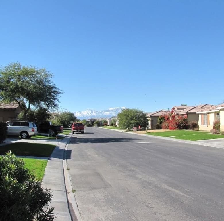 Beautiful residential street in Indio with spacious homes and lush greenery.