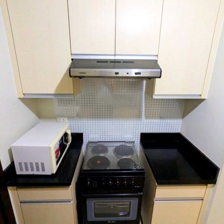 Compact kitchen with stove, microwave, and cabinets in Kroma Tower Manila.