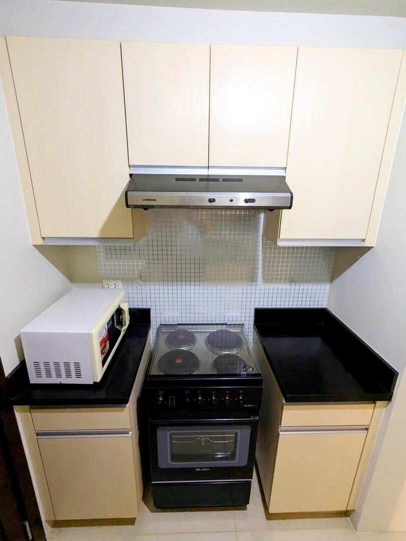 Compact kitchen with stove, microwave, and cabinets in Kroma Tower Manila.