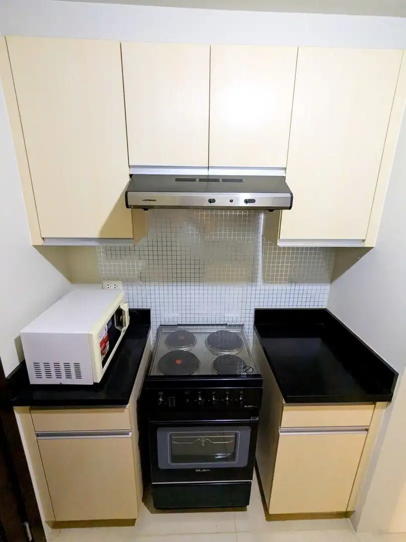 Compact kitchen with stove, microwave, and cabinets in Kroma Tower Manila.