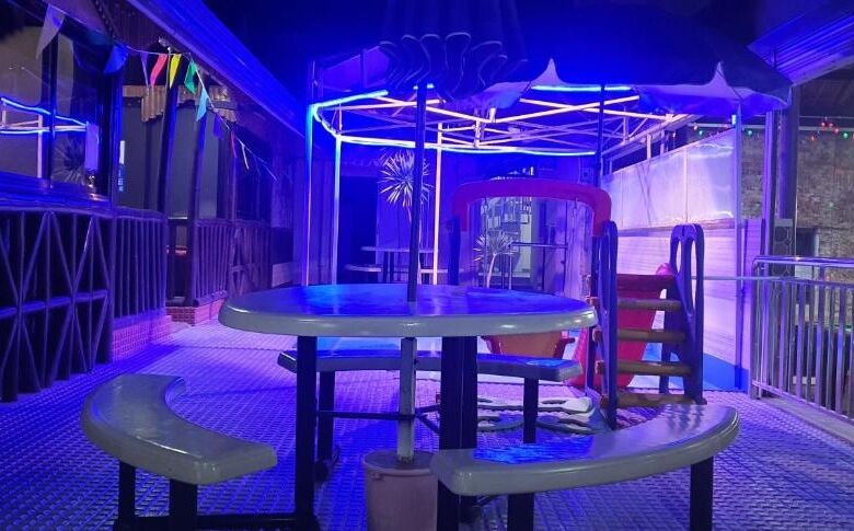Brightly lit indoor resort area with colorful neon lights and playful seating arrangements.