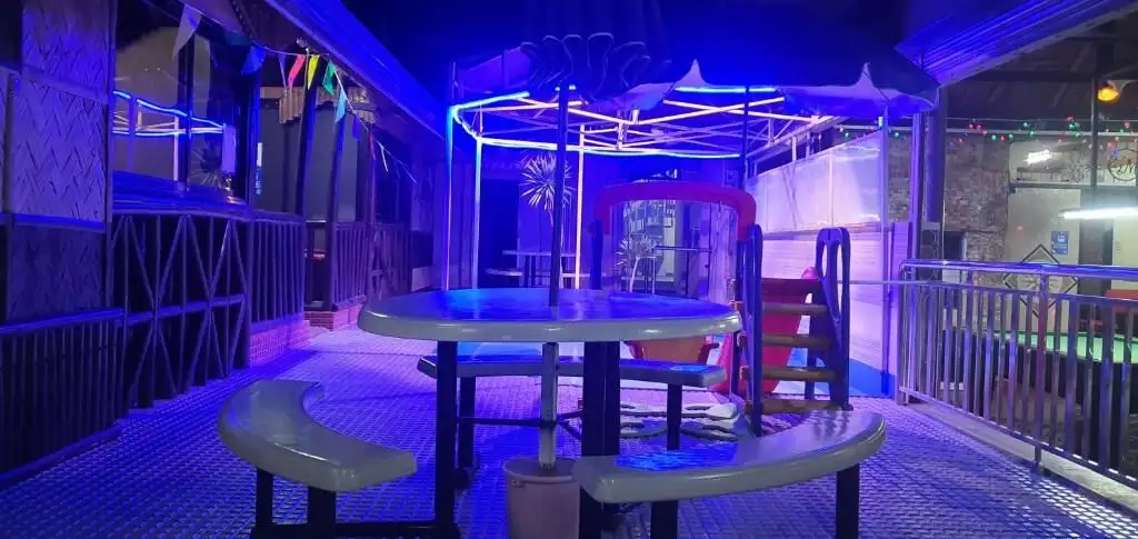 Brightly lit indoor resort area with colorful neon lights and playful seating arrangements.