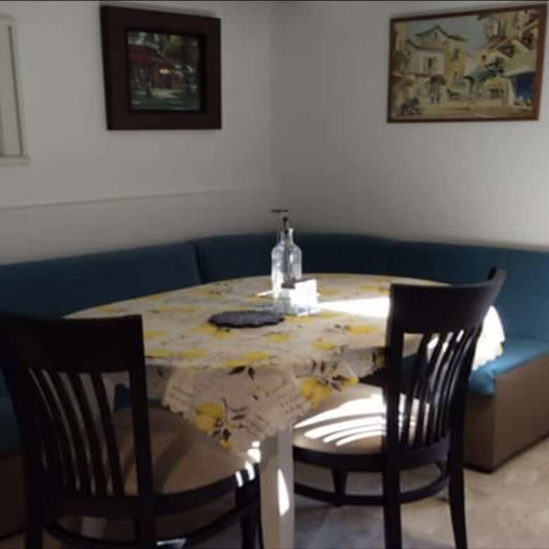 Interior view of a dining area with a round table, chairs, and wall art in a villa in Rogulyat Mlech.