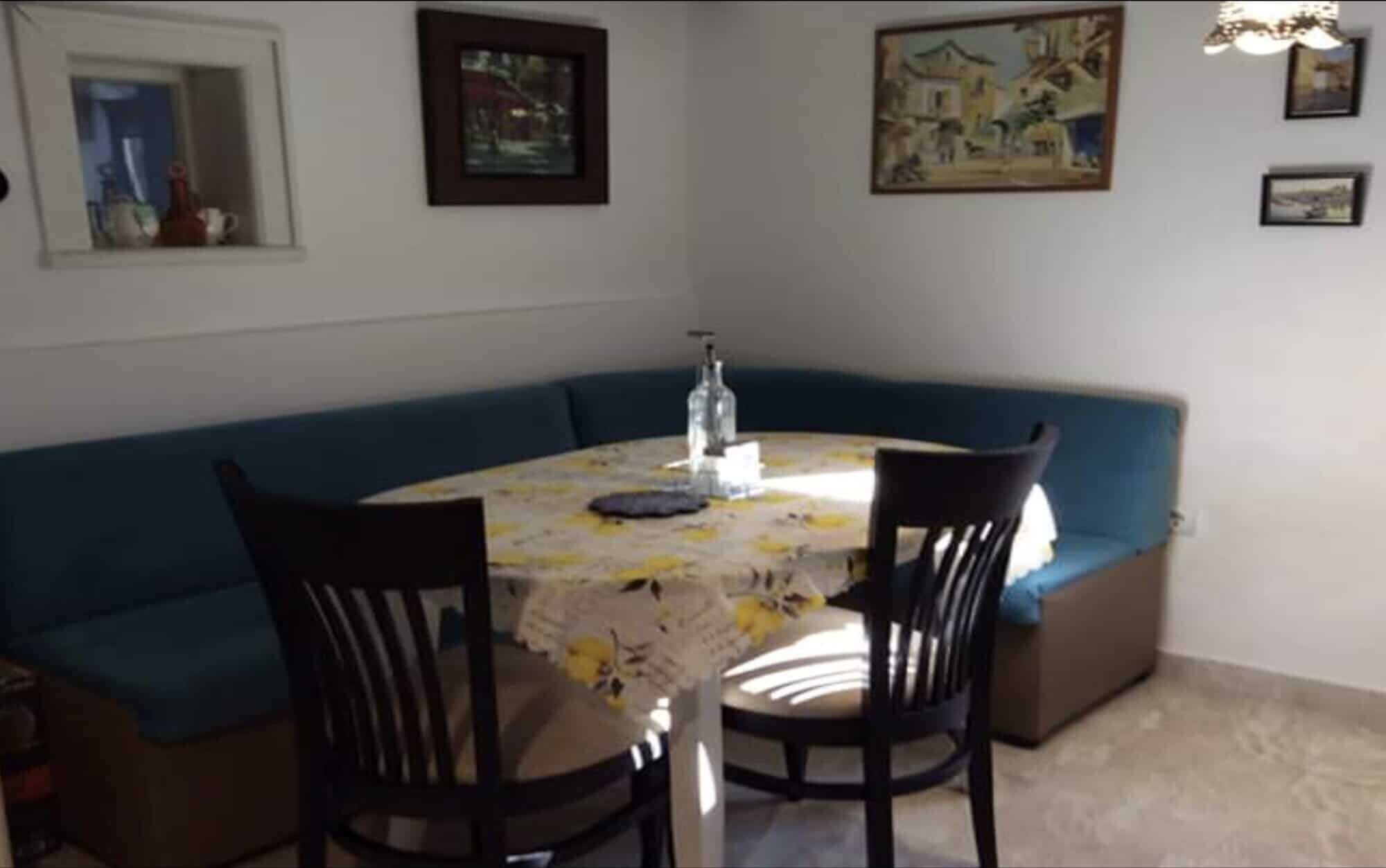 Interior view of a dining area with a round table, chairs, and wall art in a villa in Rogulyat Mlech.