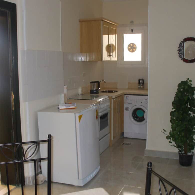 Modern kitchen with appliances in Hurghada apartment, featuring a washing machine, oven, and wooden.
