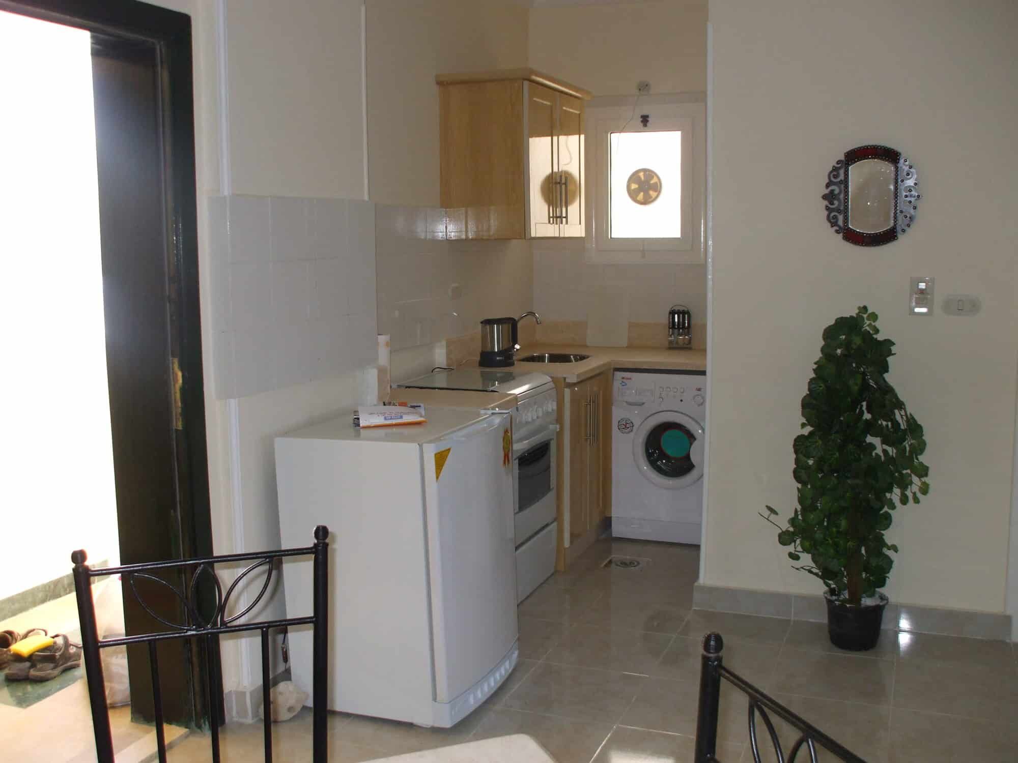 Modern kitchen in Hurghada apartment with appliances and decor Modern kitchen with appliances in Hurghada apartment, featuring a washing machine, oven, and wooden.