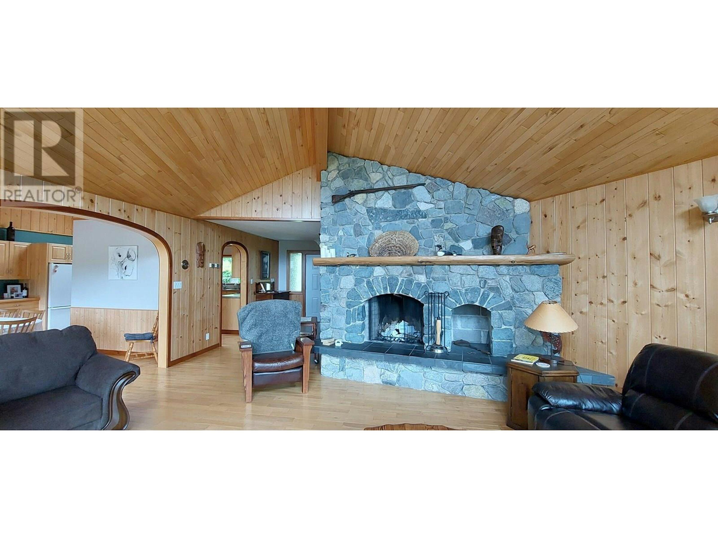 Charming 4-Bedroom Estate in Bella Coola Spacious living room with a stone fireplace and wooden accents in this beautiful estate for sale in.