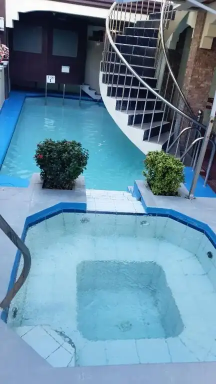 Modern hotel pool with spiral staircase and lush greenery in Cavite property listing.
