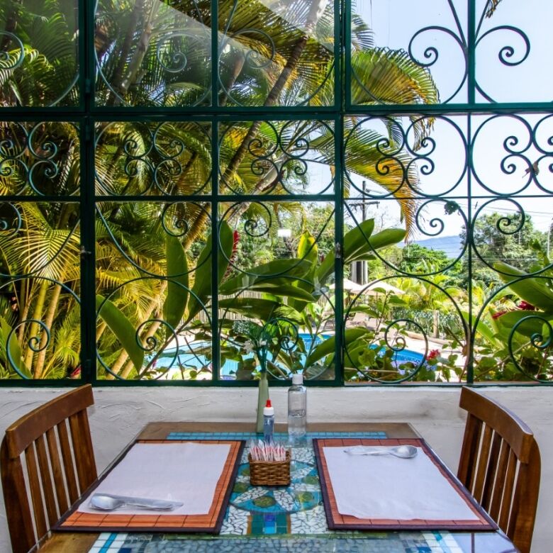 Cozy dining area with a view of lush tropical garden and pool at a boutique hotel in Ilhabela. Perfe.
