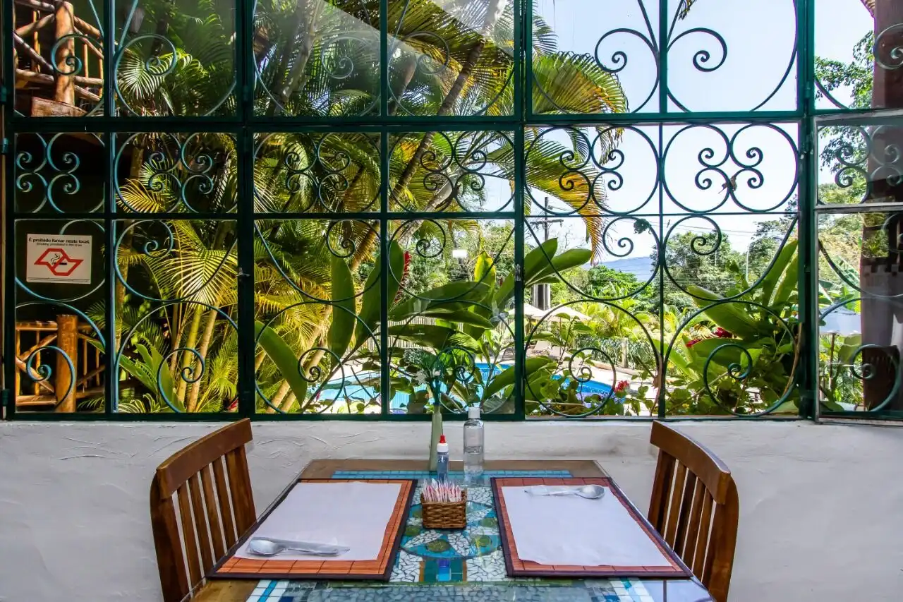 Cozy dining area with a view of lush tropical garden and pool at a boutique hotel in Ilhabela. Perfe.