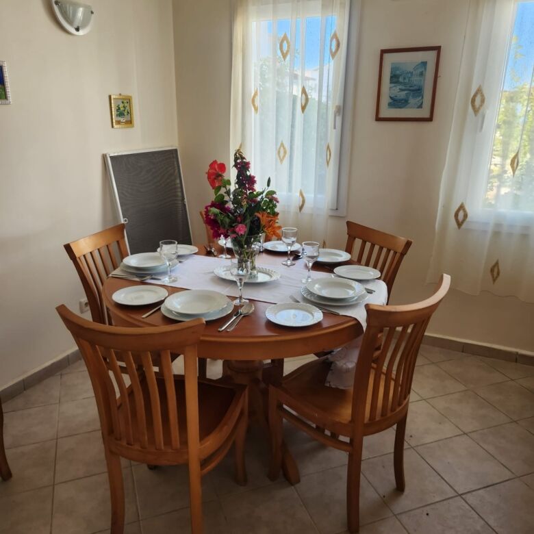 Spacious dining room with a round wooden table set for six, bright natural light, and elegant decor.
