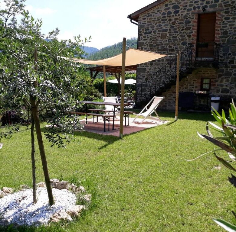 Elegant stone house with outdoor seating area in lush garden setting.