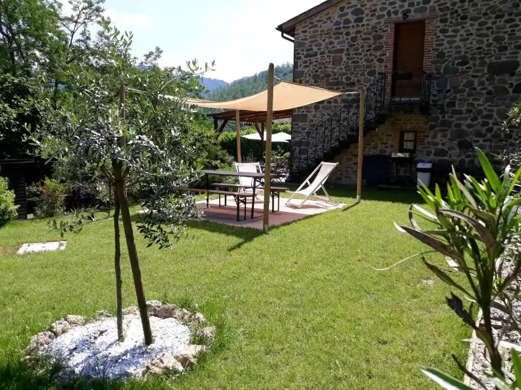 Elegant stone house with outdoor seating area in lush garden setting.