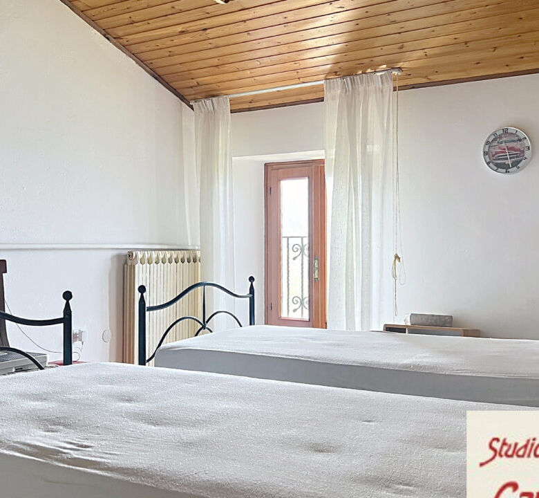 Spacious bedroom in Fivizzano, Tuscany, featuring two single beds, wooden ceiling, and natural light.
