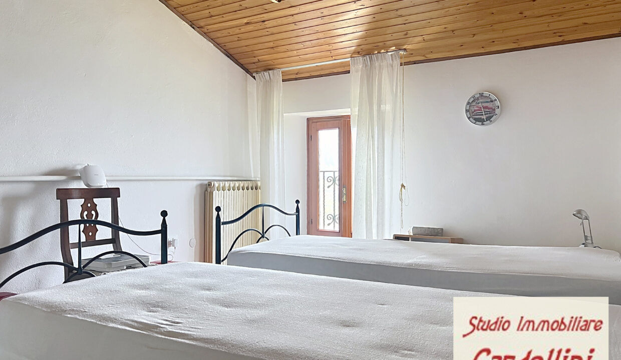 Charming Fivizzano Bedroom with Rustic Decor Spacious bedroom in Fivizzano, Tuscany, featuring two single beds, wooden ceiling, and natural light.