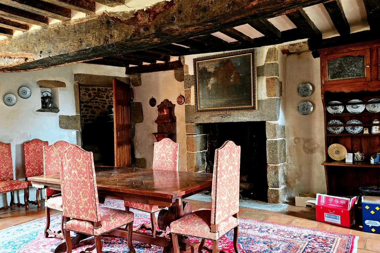Luxury 5 Bed Le Manoir de Dougeru Charming interior of a historic manor with exposed wooden beams and antique furnishings.