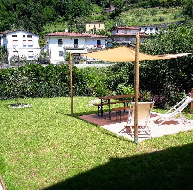 Beautiful outdoor garden with sunshade, lounge chairs, and scenic hillside views in Bagni di Lucca.