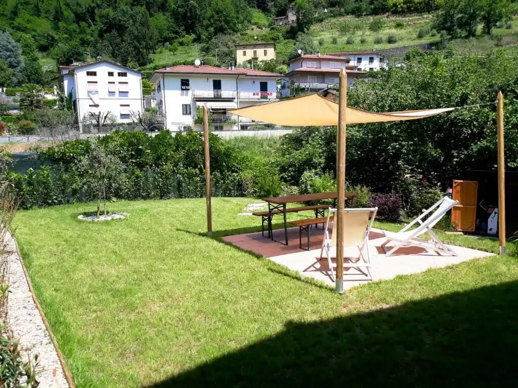 Beautiful outdoor garden with sunshade, lounge chairs, and scenic hillside views in Bagni di Lucca.