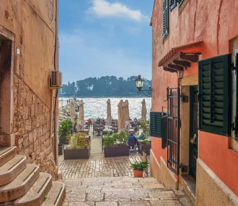 Charming coastal alley with colorful buildings and sea view in Skrinjari, Istria.