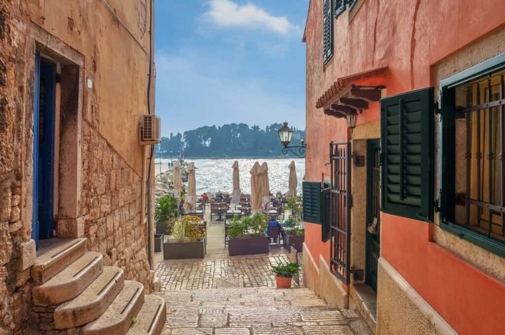 Luxury 2 Bed Villa For Sale in Skrinjari Istria Charming coastal alley with colorful buildings and sea view in Skrinjari, Istria.