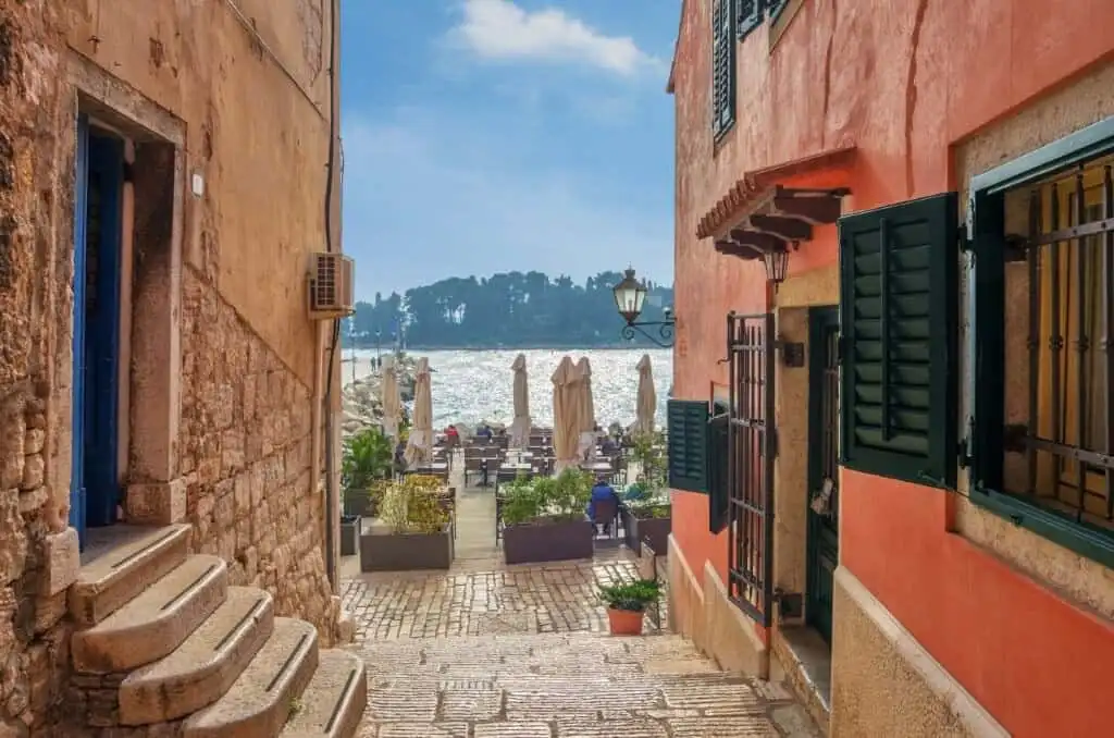 Charming coastal alley with colorful buildings and sea view in Skrinjari, Istria.