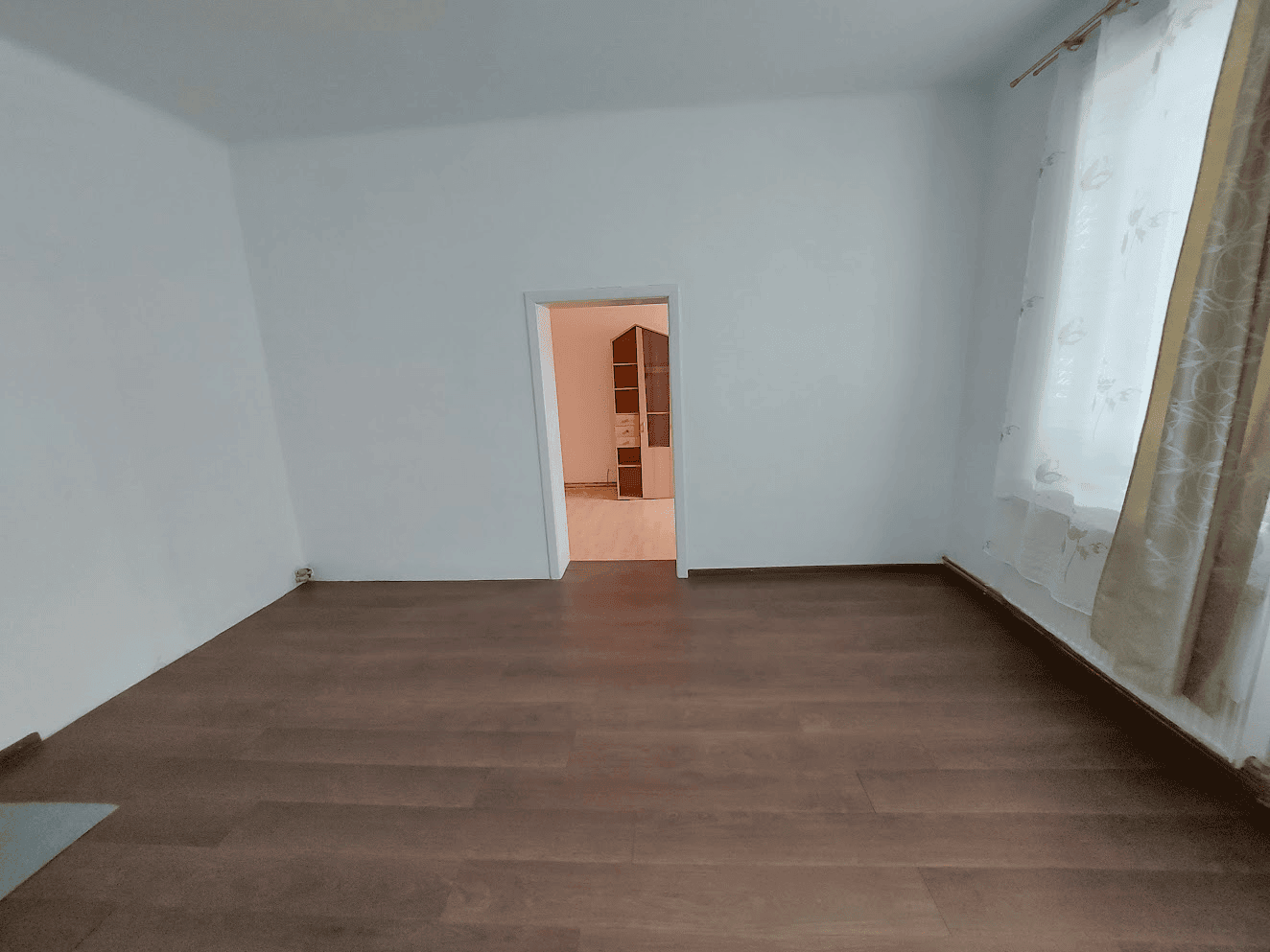 Modern apartment interior with wooden flooring in Wilhelmsburg. Spacious living room with large window and natural light, ideal for family living.