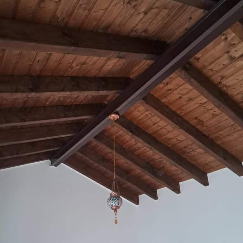 Wooden ceiling with beams and a hanging decorative lamp in a villa.
