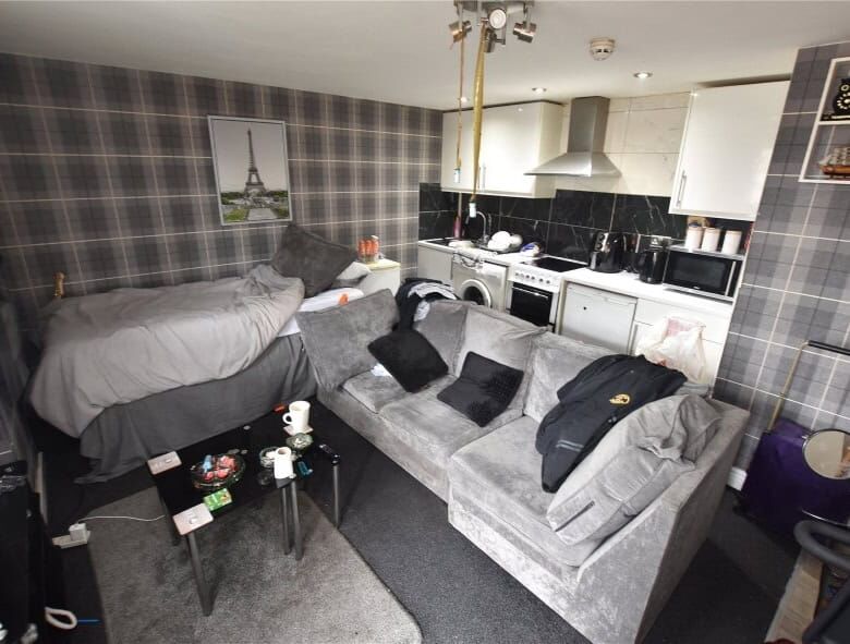 Interior view of a Leeds apartment with a sofa, bed, and kitchen area.