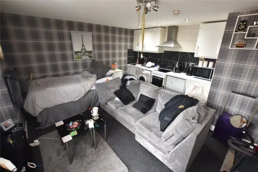 Interior view of a Leeds apartment with a sofa, bed, and kitchen area.