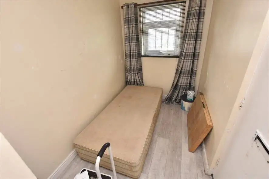 Compact room in Leeds with a single bed and window view, ideal for rental investment.