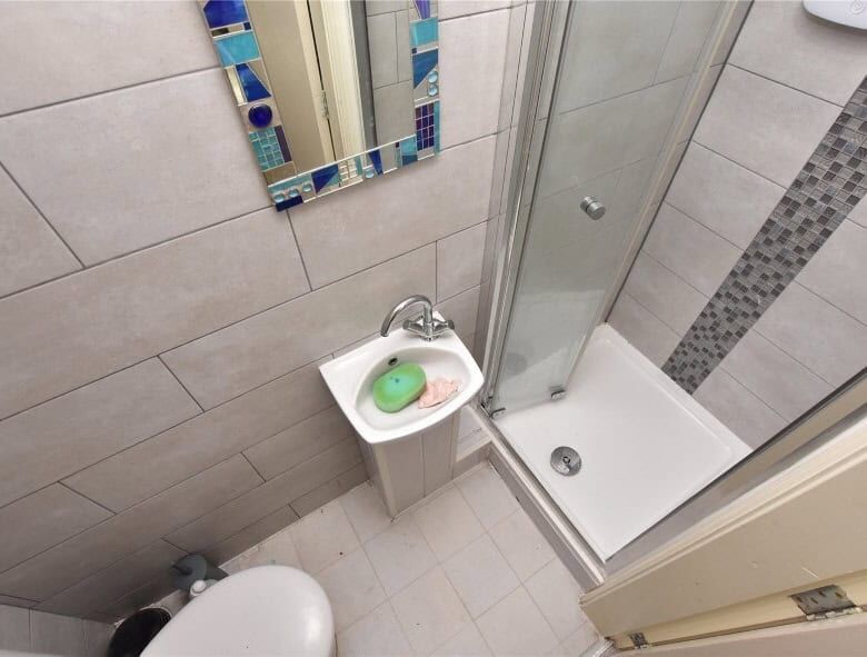 Bathroom with shower, sink, and tiled walls in Leeds property for sale.