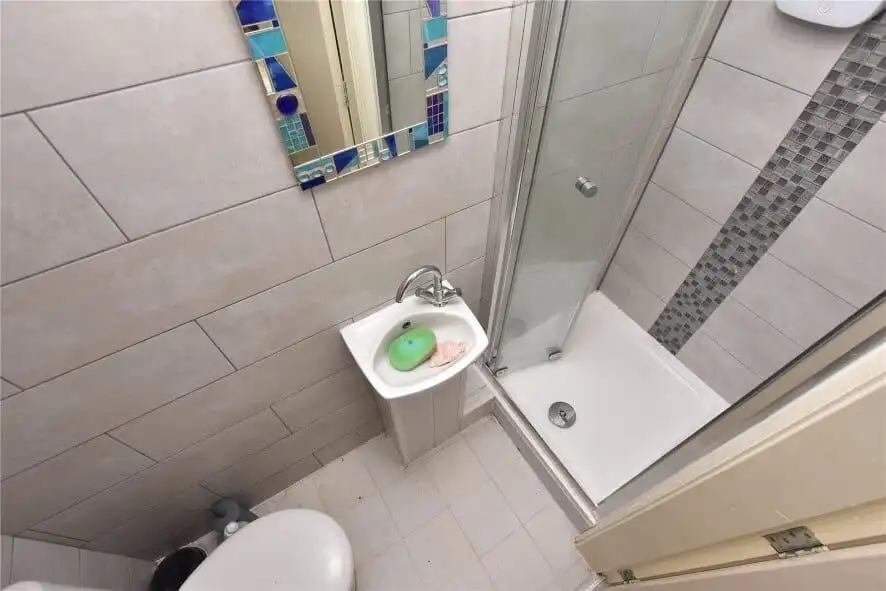Bathroom with shower, sink, and tiled walls in Leeds property for sale.