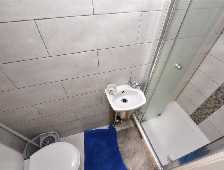 Bathroom with shower, toilet, and sink in Leeds property complex for sale.