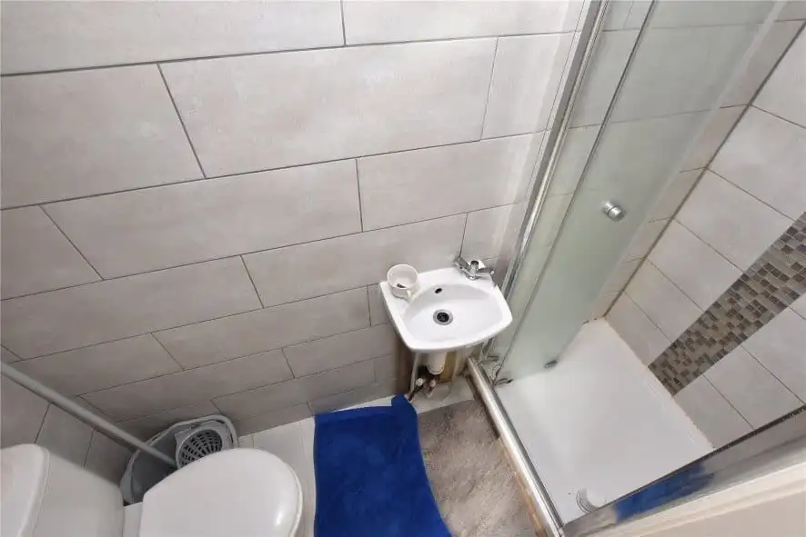 Bathroom with shower, toilet, and sink in Leeds property complex for sale.