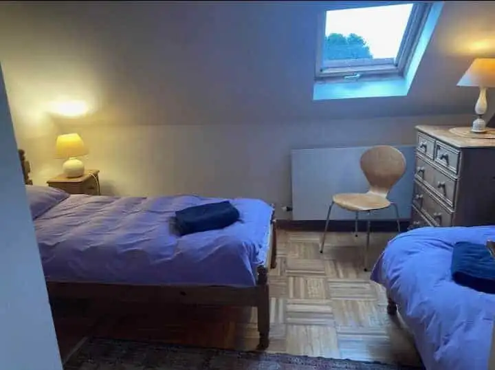 Spacious bedroom in Sorrus featuring two beds, a window with scenic views, and cozy lighting. Ideal.